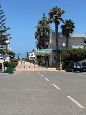 an empty parking lot with palm trees and a building at Séjour cosy à Palm Beach Mansouriah in Pont Blondin