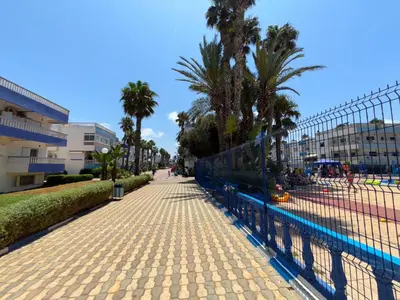 a fence next to a sidewalk with palm trees at Séjour cosy à Palm Beach Mansouriah in Pont Blondin