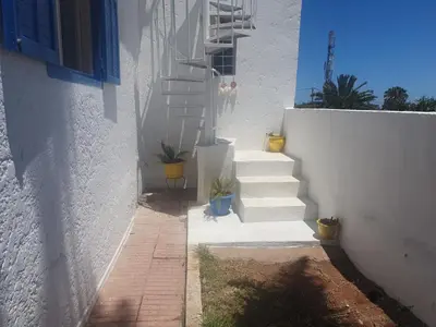 a stairway leading up to a white building with potted plants at Villa plage david in Kasba Bou Hamira