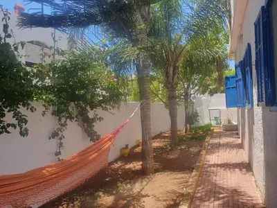a hammock hanging between two palm trees next to a building at Villa plage david in Kasba Bou Hamira
