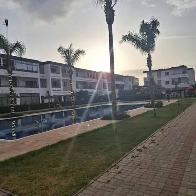 a building with palm trees next to a body of water at Appartement à 10min de la mer in Mansouria