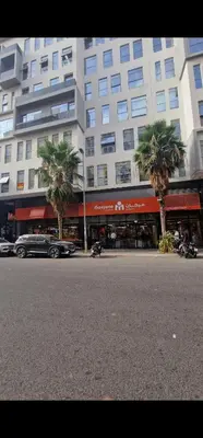 a large building with palm trees in front of a street at 2Roms 5mn Palmier Maarif Distriktet Wifi Rapide A4 in Casablanca
