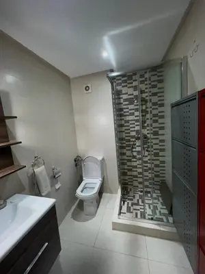 a bathroom with a toilet and a glass shower at Appartement Chaleureux in Bouznika