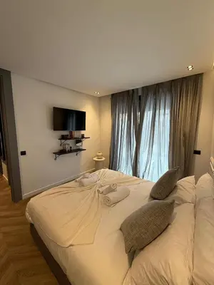 a bedroom with a large bed with a tv on the wall at Central Luxury Apartment with Fast Fiber WiFi, Terrace & Free Parking in Casablanca Close To KFC MCDO & School Group La Résidence Boulevard 2 Mars in Casablanca