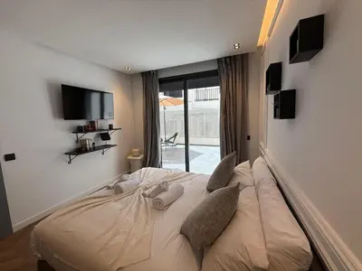 a bedroom with a bed with pillows and a television at Central Luxury Apartment with Fast Fiber WiFi, Terrace & Free Parking in Casablanca Close To KFC MCDO & School Group La Résidence Boulevard 2 Mars in Casablanca