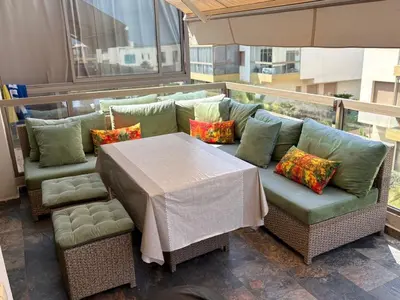 a table and a couch and a table and chairs at Appartement vue piscine - Pour Famille - Blue Beach SIDI RAHAL in Sidi Rahal