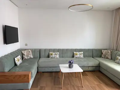 a living room with a green couch and a table at Appartement vue piscine - Pour Famille - Blue Beach SIDI RAHAL in Sidi Rahal