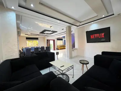 a waiting room with black couches and a tv at Rabat sidi yahya zaër in Sidi Yahia az Zaʼer