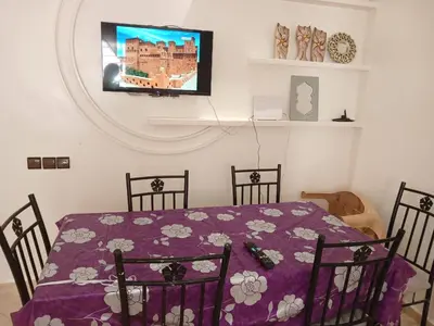 a dining room with a table and a tv on the wall at Kettani bouznika in Bouznika