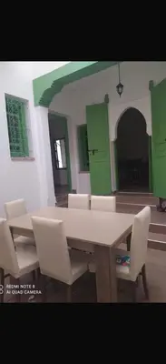 a table and chairs in a room with green cabinets at Green house in Sidi Yahia az Zaʼer