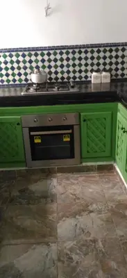 a kitchen with green cabinets and a stove at Green house in Sidi Yahia az Zaʼer