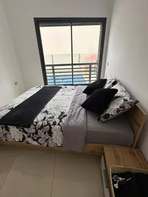 a bed in a room with a large window at Appartement calme in Bouznika
