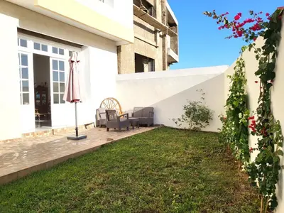 a patio with an umbrella and a lawn at villa dans el mansouria in Mansouria