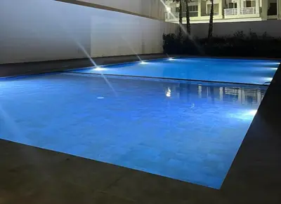 a blue swimming pool with lights in a building at Costa house in Bouznika