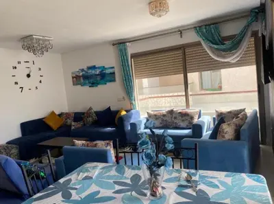 a living room with blue couches and a clock on the wall at Puerto banus in Mansouria