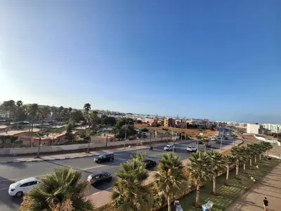 a parking lot with palm trees and the ocean at البحر والشمس والطبيعه in Pont Blondin