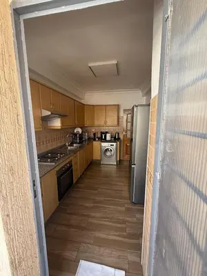 a kitchen with wooden cabinets and a stainless steel refrigerator at Appartement 3 pièces à Mohammédia Proche Marjane, plage & restaurants in Mohammedia