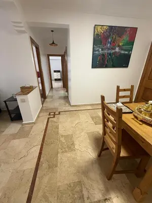 a dining room with a table and a painting on the wall at Appartement 3 pièces à Mohammédia Proche Marjane, plage & restaurants in Mohammedia