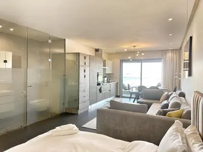 a living room with two couches and a kitchen at 1-Marina Luma oceane-terrasse sur mer in Casablanca