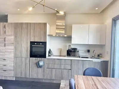a kitchen with white cabinets and a table in a room at 1-Marina Luma oceane-terrasse sur mer in Casablanca