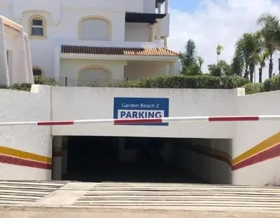a parking garage with a sign in front of a building at Garden Beach 2 in Sidi Rahal