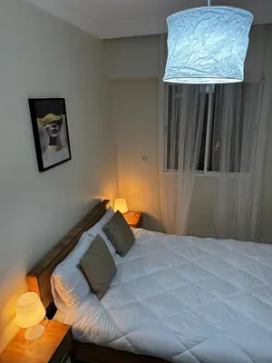 a bedroom with a large white bed and a chandelier at Apprt 2min de la Gare,Wi-Fi Fibre, Netflix ,PS4 in Settat