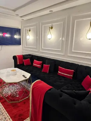 a living room with a black couch and red pillows at Apartment with pool view in Mansouria