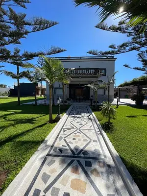 a walkway in front of a building with trees at Villa Royale Prestige Safaa in Dar Bouazza