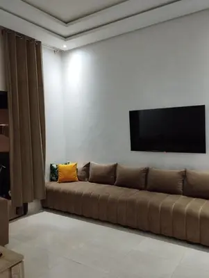 a living room with a couch and a flat screen tv at Appartement à louer à Bouznika avec piscine in Bouznika