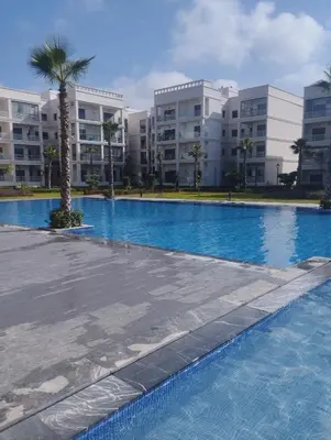 a large swimming pool in front of some apartment buildings at Appartement à louer à Bouznika avec piscine in Bouznika