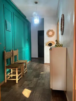 a kitchen with green cabinets and a chair and a refrigerator at Cozy apartment near the airport in Deroua