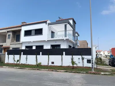 a white building with a black fence next to a street at Villa Chez Badre with Pool High Standing in Sidi Rahal