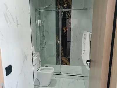 a bathroom with a toilet and a glass shower at Villa Chez Badre with Pool High Standing in Sidi Rahal