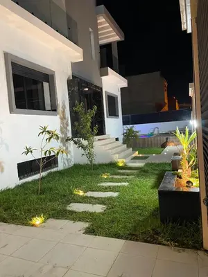 a house with a pathway in the yard at night at Villa Chez Badre with Pool High Standing in Sidi Rahal
