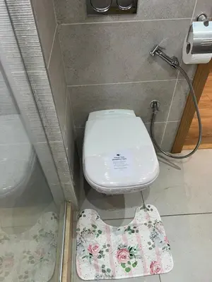 a bathroom with a toilet with a flower rug next to it at Appartement Élégance Cosy in Rabat