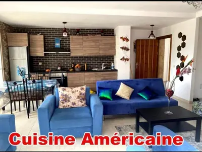 a living room with a blue couch and a kitchen at Mohmmadia puerto banus in Mohammedia