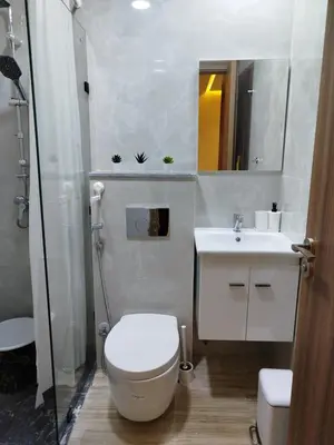 a white bathroom with a toilet and a sink at Studio à louer CFC in Casablanca
