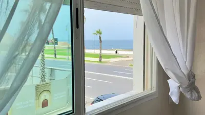 a window with a view of a street and the ocean at Immense appartement familial vue sur mer in Rabat