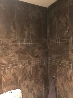 a bathroom with a toilet and a tiled wall at Apartment Galia Mohammedia in Mohammedia