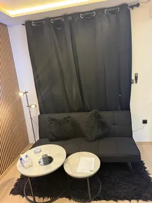 a living room with a black couch with two tables at Studio au Cœur de Rabat in Rabat