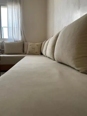 a large white bed in a room with a couch at An Elegant apartment, Quiet Stay with Moroccan Touch in Dar Bouazza