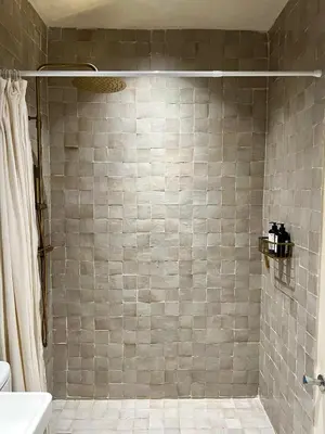 a bathroom with a shower with a tiled wall at An Elegant apartment, Quiet Stay with Moroccan Touch in Dar Bouazza