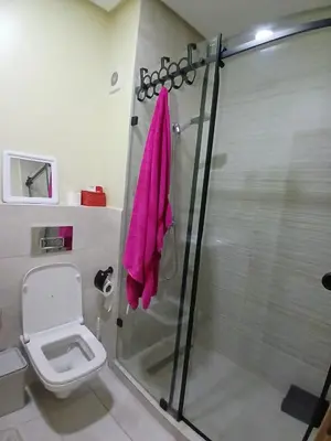 a bathroom with a shower with a pink towel at Duplex Vue Piscine et Jardin Océan Park à Zenata City Eco in Aïn Harrouda