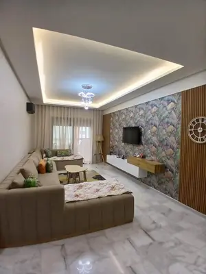 a living room with a large couch and a tv at Duplex Vue Piscine et Jardin Océan Park à Zenata City Eco in Aïn Harrouda