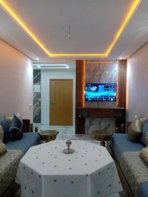 a living room with a table and a fireplace at Perle Bouznika in Bouznika