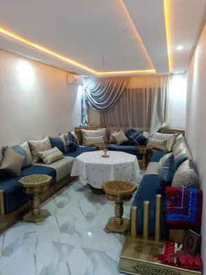 a living room with a blue couch and a table at Perle Bouznika in Bouznika