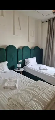 two beds in a room with green chairs at Appartement cosy près Abdelmoumen Maarif in Casablanca