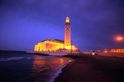 a building with a clock tower on the beach at night at La Corniche - Seaside - Hassan II in Casablanca