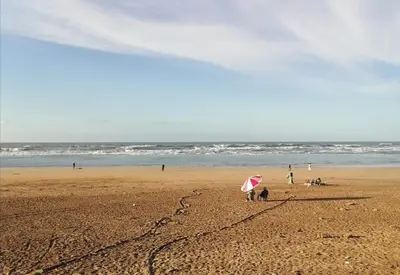 a person with a pink umbrella on a beach at plénitude in Mohammedia