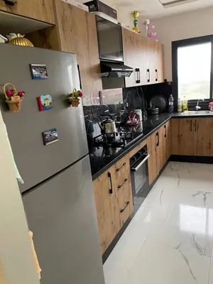 a kitchen with a white refrigerator and wooden cabinets at Apparemment propre pour les familles in Casablanca